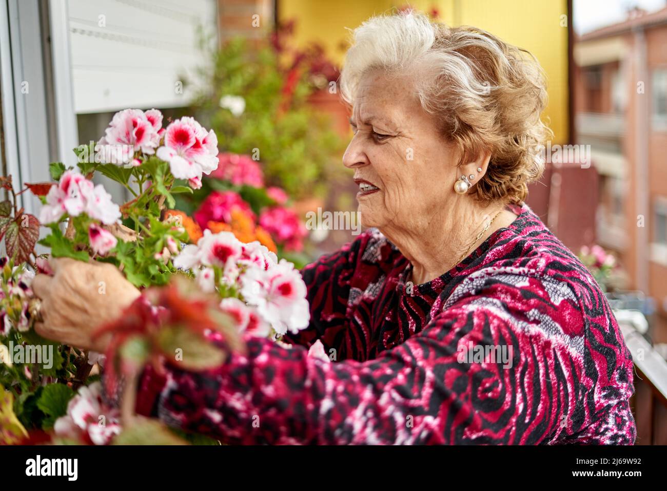 Stolze ältere Frau mit blühenden Blumen Stockfoto