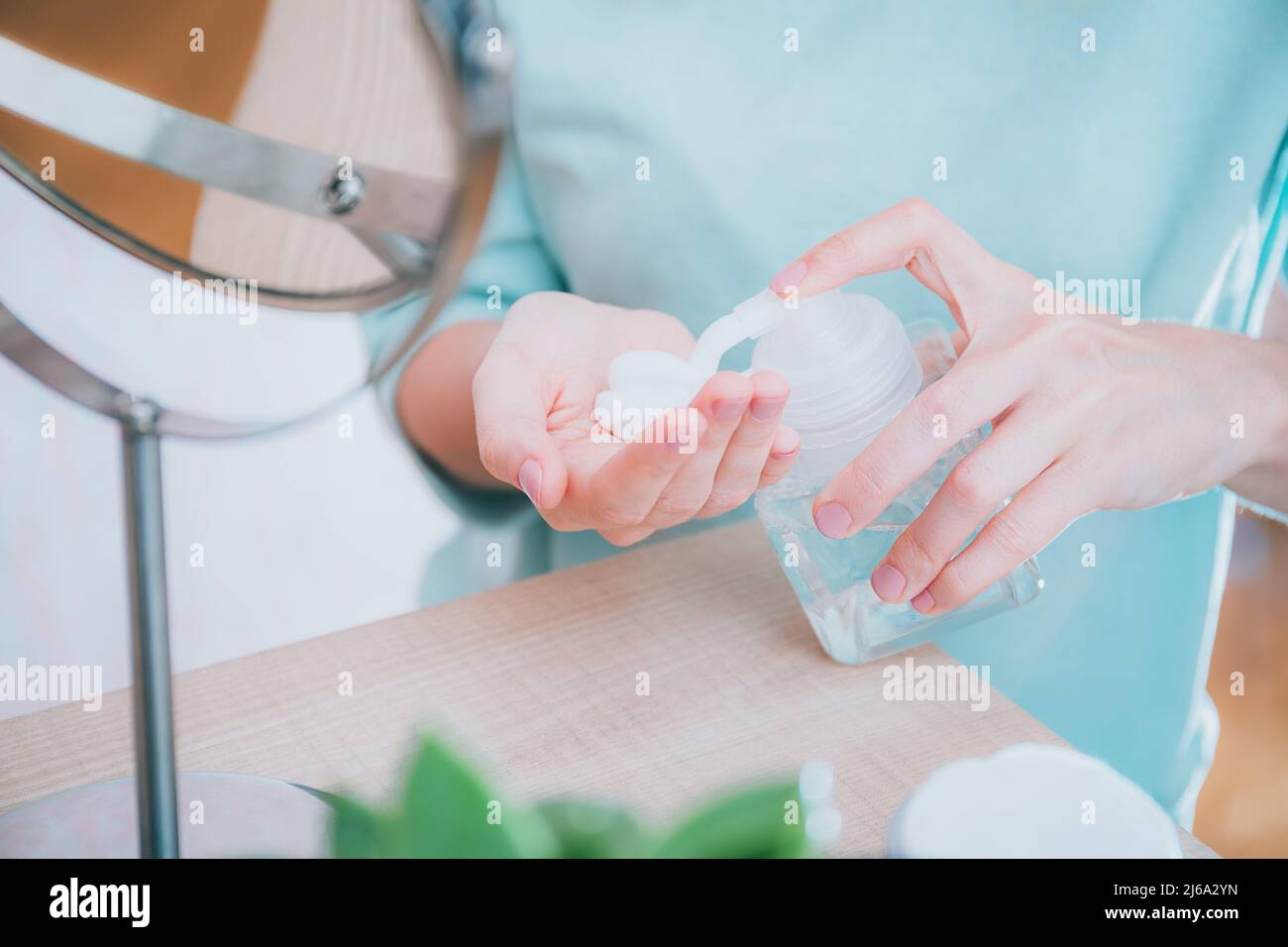 Mädchen quetscht Hautpflegemittel aus dem Spender in die Handfläche vor dem Spiegel. Hautpflege, Gesichtsreinigung mit Schaum, Naturkosmetik Stockfoto