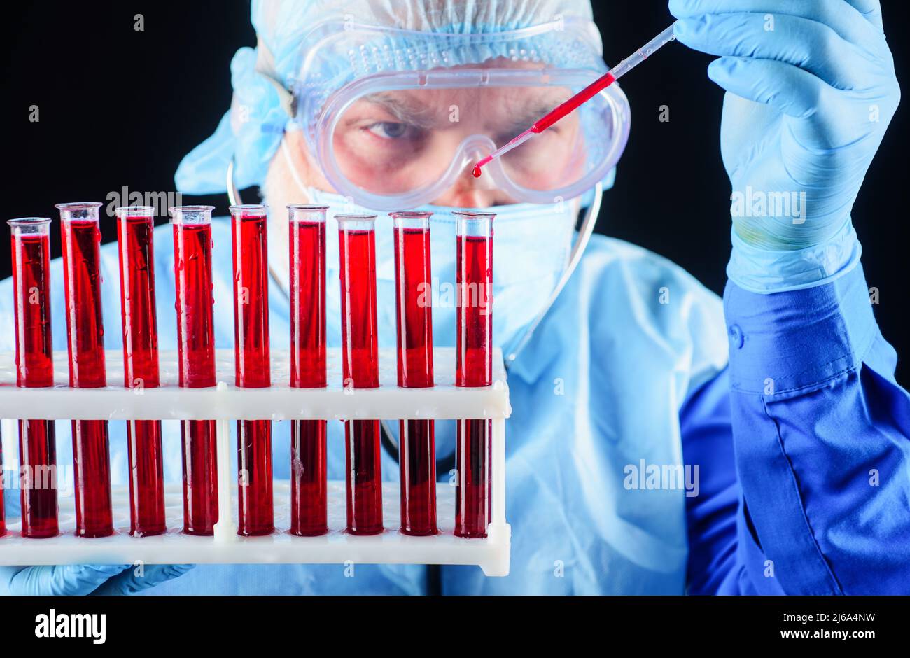 Wissenschaftler im Bereich Schutzabnutzung, der Blutprobe analysiert. Labortechniker mit Reagenzgläsern im Rack. Stockfoto