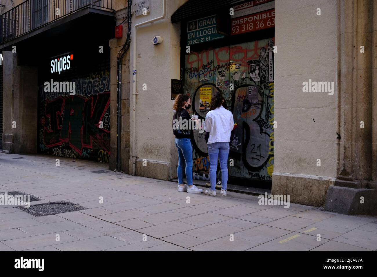 Zwei Frauen vor Graffiti verzierten Türen in Barcelona, Spanien Stockfoto