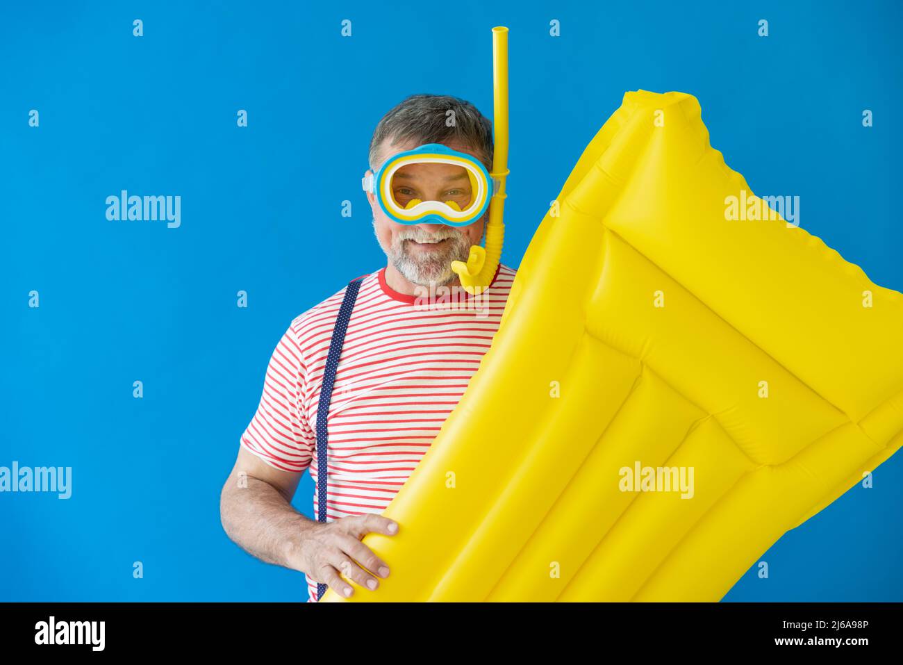 Glücklicher älterer Mann, bereit zu reisen. Person mit gelber Luftmatratze. Sommerurlaub und Urlaubskonzept Stockfoto