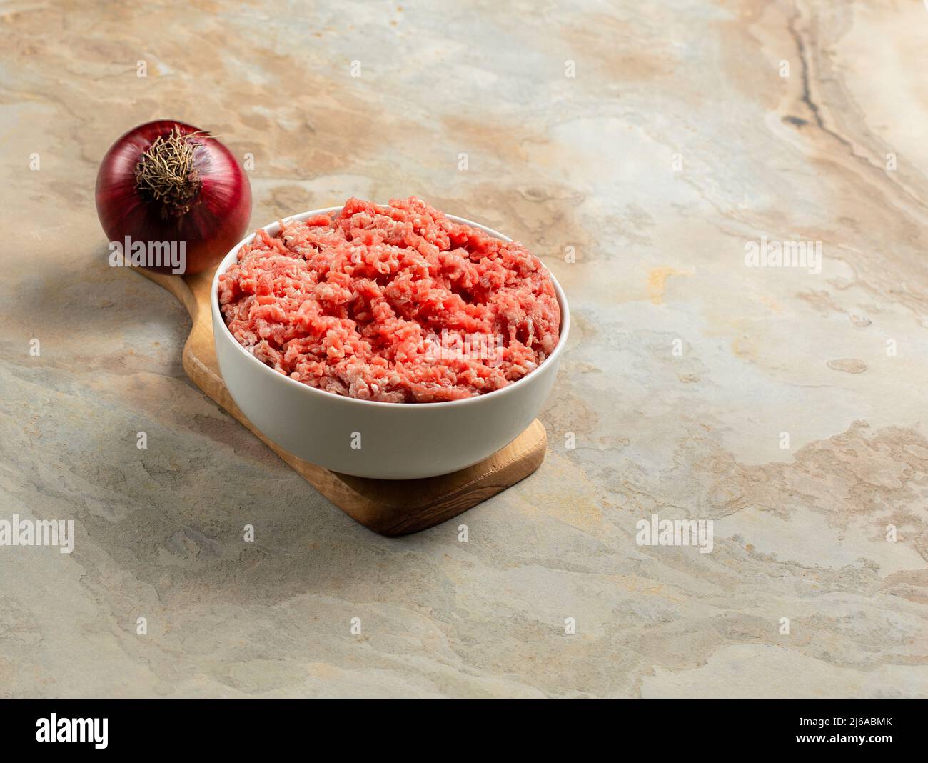 Teller mit frisch gemahlenem Rindfleisch, roter Zwiebel auf braunem Vintage-Hintergrund, Platz für Text, Stockfoto Stockfoto