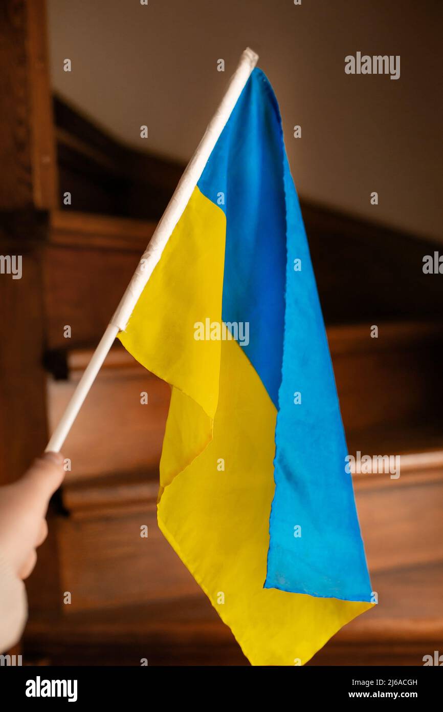 Hand mit kleiner ukrainischer Flagge Holztreppe Hintergrund Stockfoto