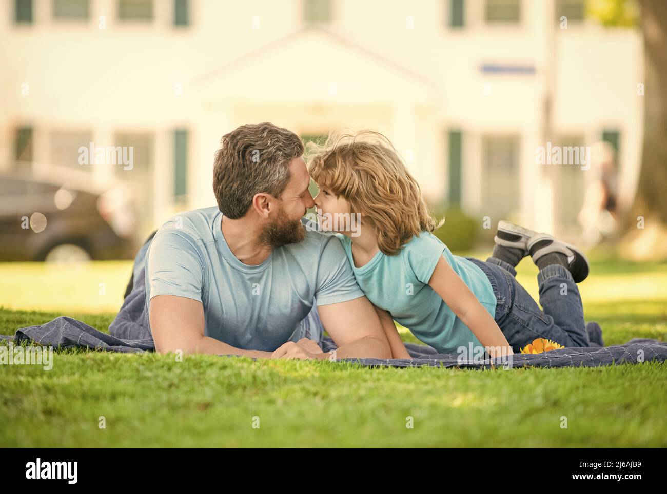Glücklicher Vater mit Sohn entspannen zusammen auf grünem Parkgras, Vaterschaft Stockfoto