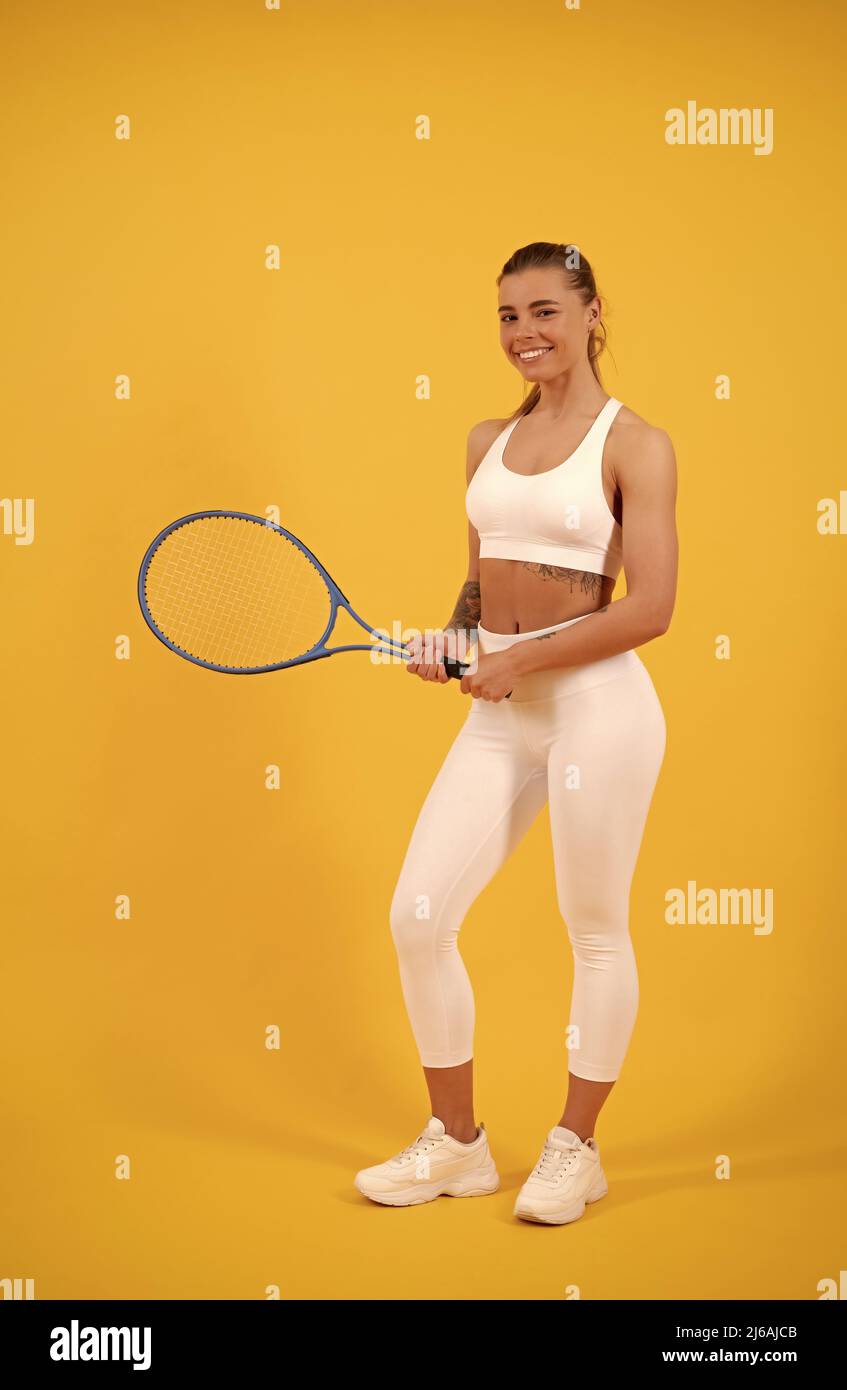 Fröhlicher Tennisspieler in Sportbekleidung mit Schläger auf gelbem Hintergrund, Athlet Stockfoto