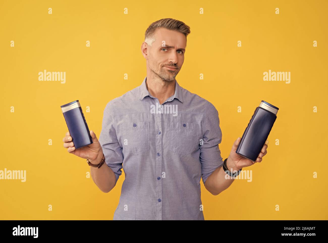 Guy wählen Shampoo-Flasche oder Haarspülung. Tägliche Gewohnheiten und persönliche Pflege. Stockfoto