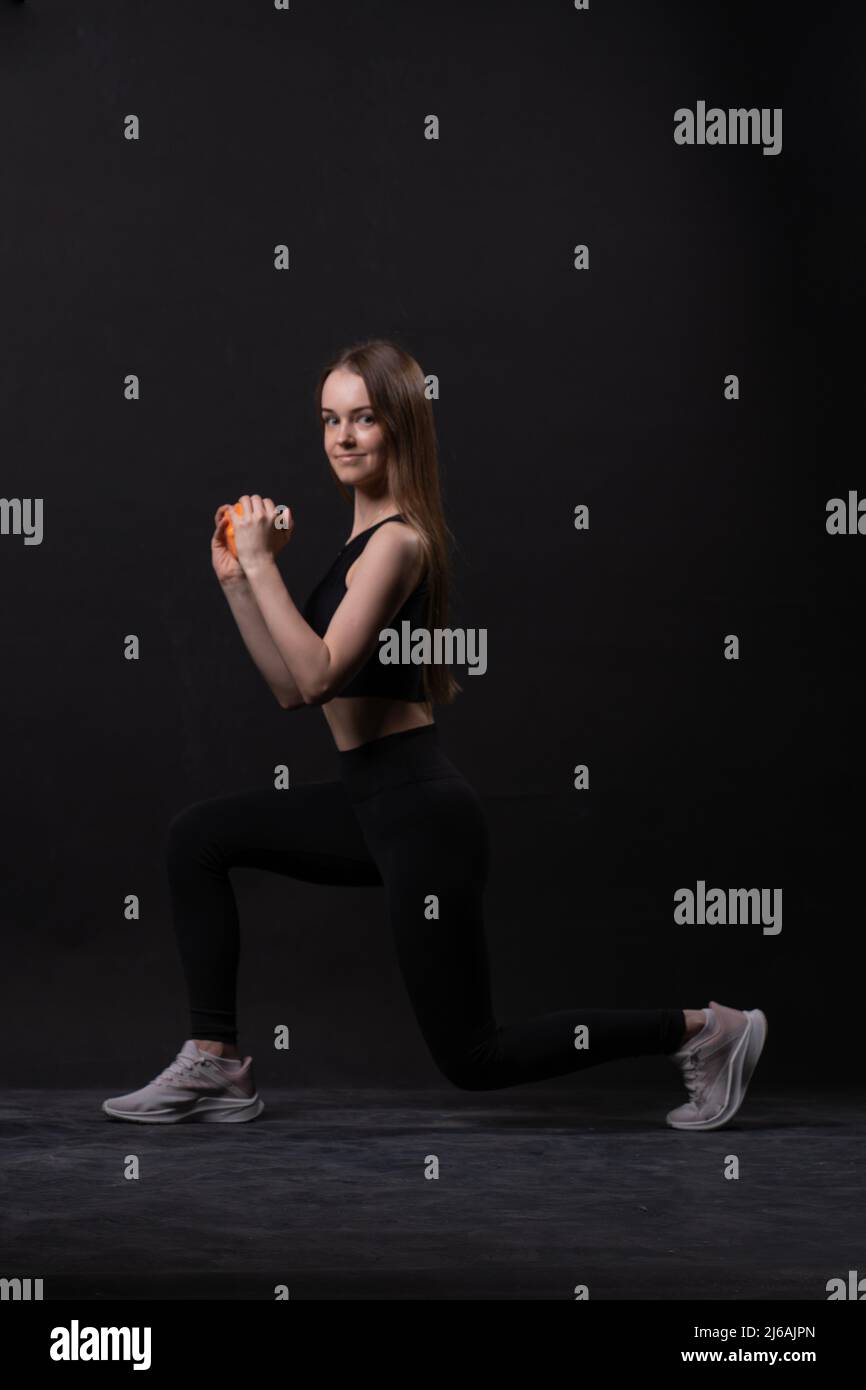 Auf Mädchen schöne Orange . Ein mit Hanteln Hintergrund schwarz orange zwei Fitness-Studio, aus Form Körper in fit für die weibliche Pflege, Aerobic plus. Aktiver Anfänger Stockfoto