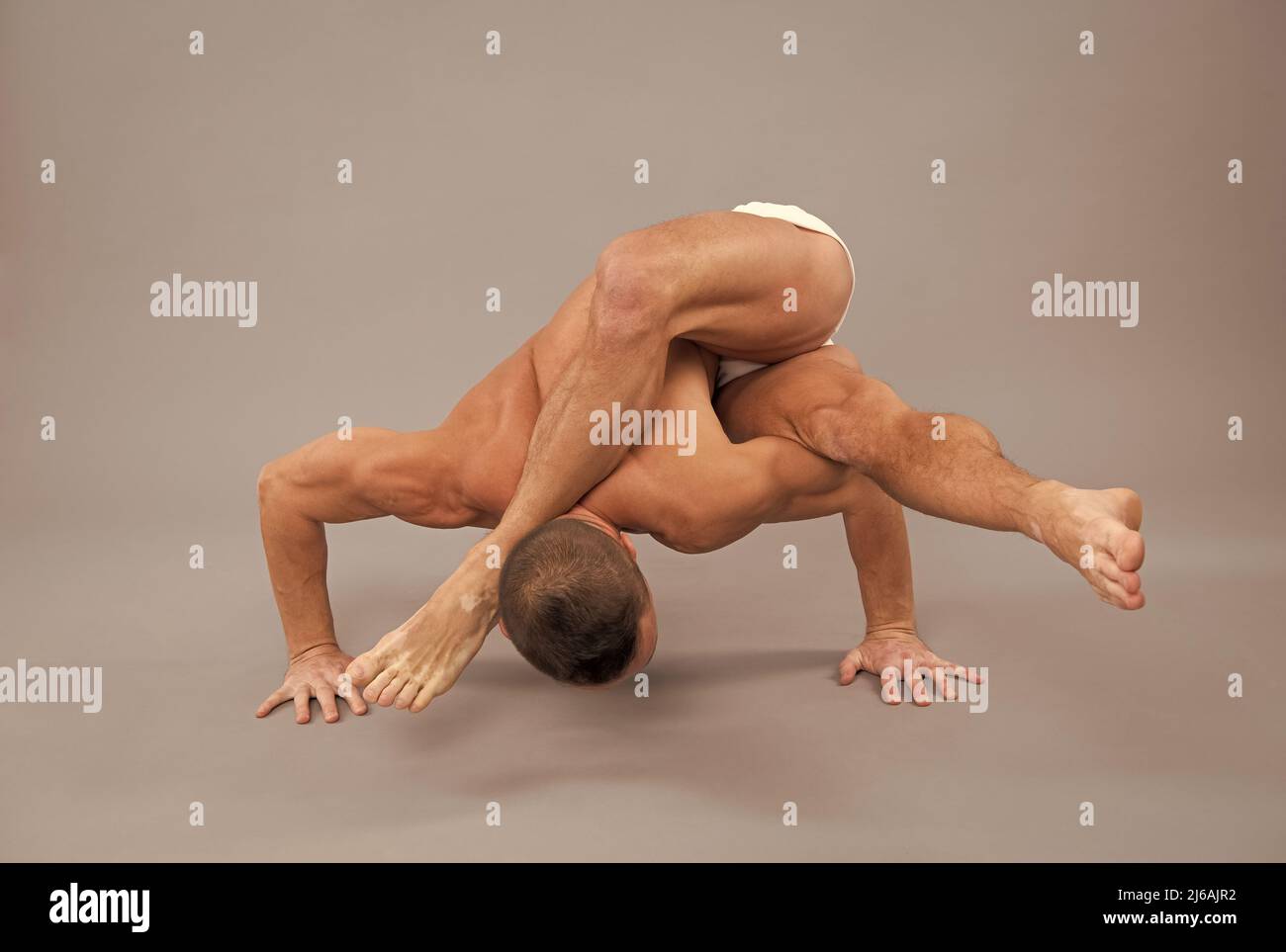 Steigern Sie Ihre Flexibilität. Mann tun Yoga grauen Hintergrund. Yogalehrer. Körperliches Training Stockfoto