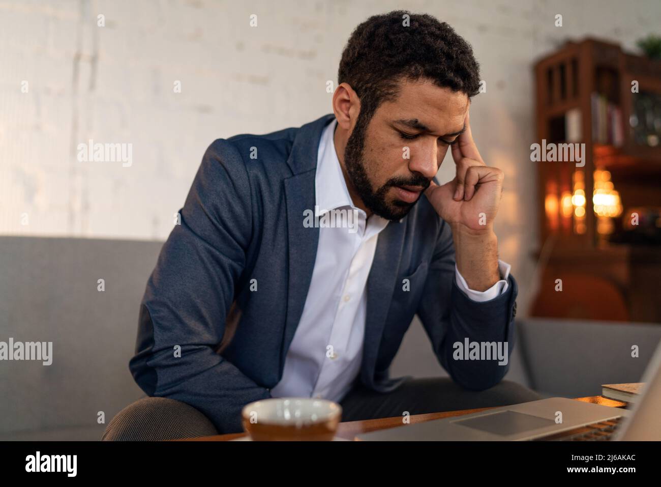 Beschäftigter junger Geschäftsmann mit Kopfschmerzen bei seiner Arbeit. Stockfoto