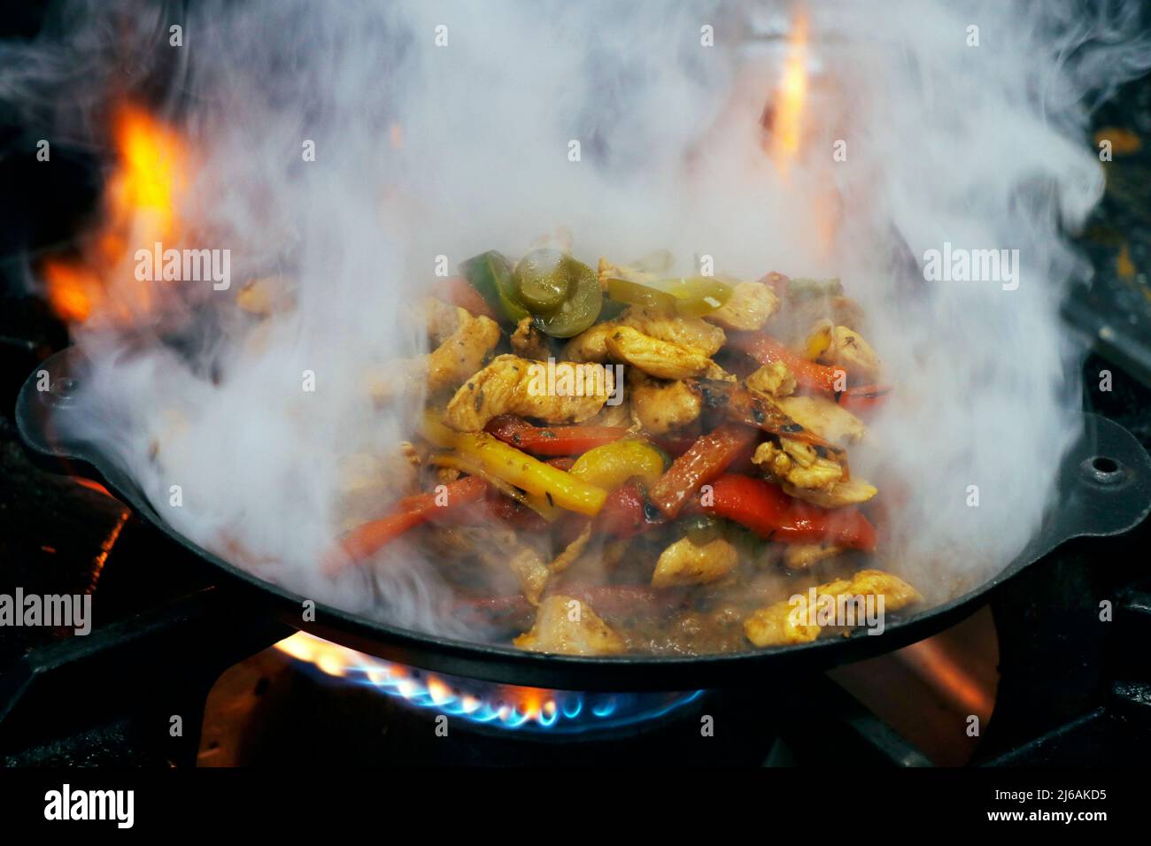 mexikanisches Essen, Fajitas mit Huhn, Rindfleisch und Paprika, serviert auf einem heißen, rauchenden, brutzelnden Teller Stockfoto