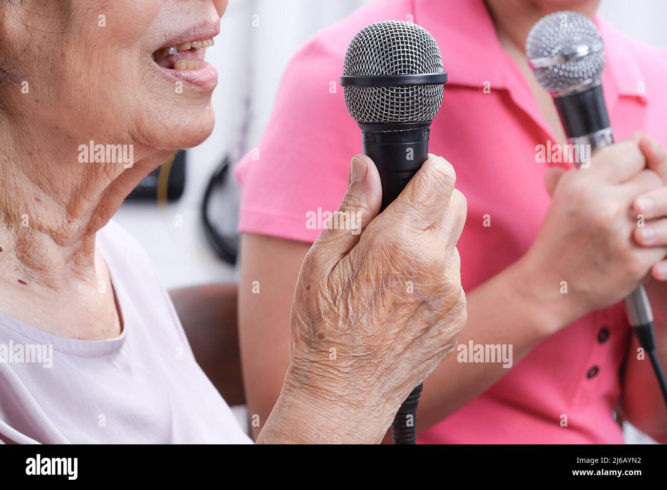 Ältere Frau singt ein Lied mit Tochter zu Hause. Stockfoto