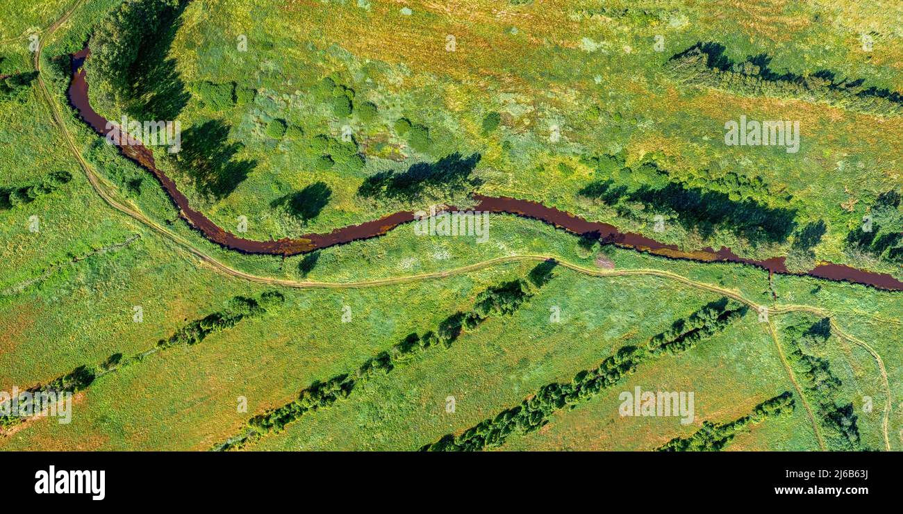 Gewundener Fluss in einem Feld oben aus der Luft. Langes Panoramabild Stockfoto