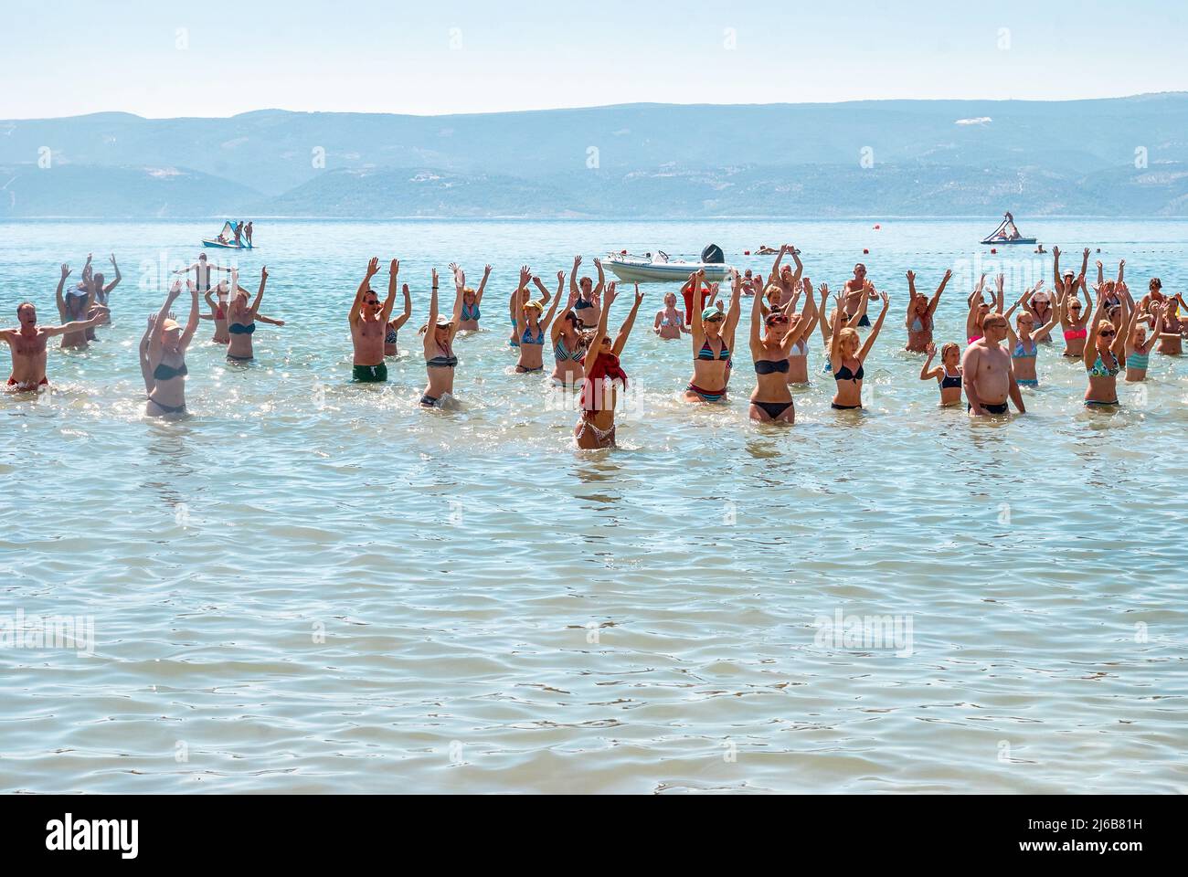 Omis, Kroatien - 19 2013. August: In Omis tanzen die Menschen im Wasser mit dem Animator gegen riesige Berge. Touristen haben Spaß im Meer bei der Party im Sommer vacat Stockfoto
