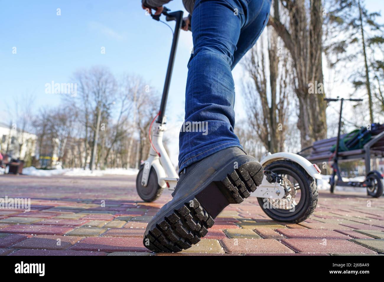 Der Typ fährt und springt im Frühjahr im Park einen Elektroroller Stockfoto