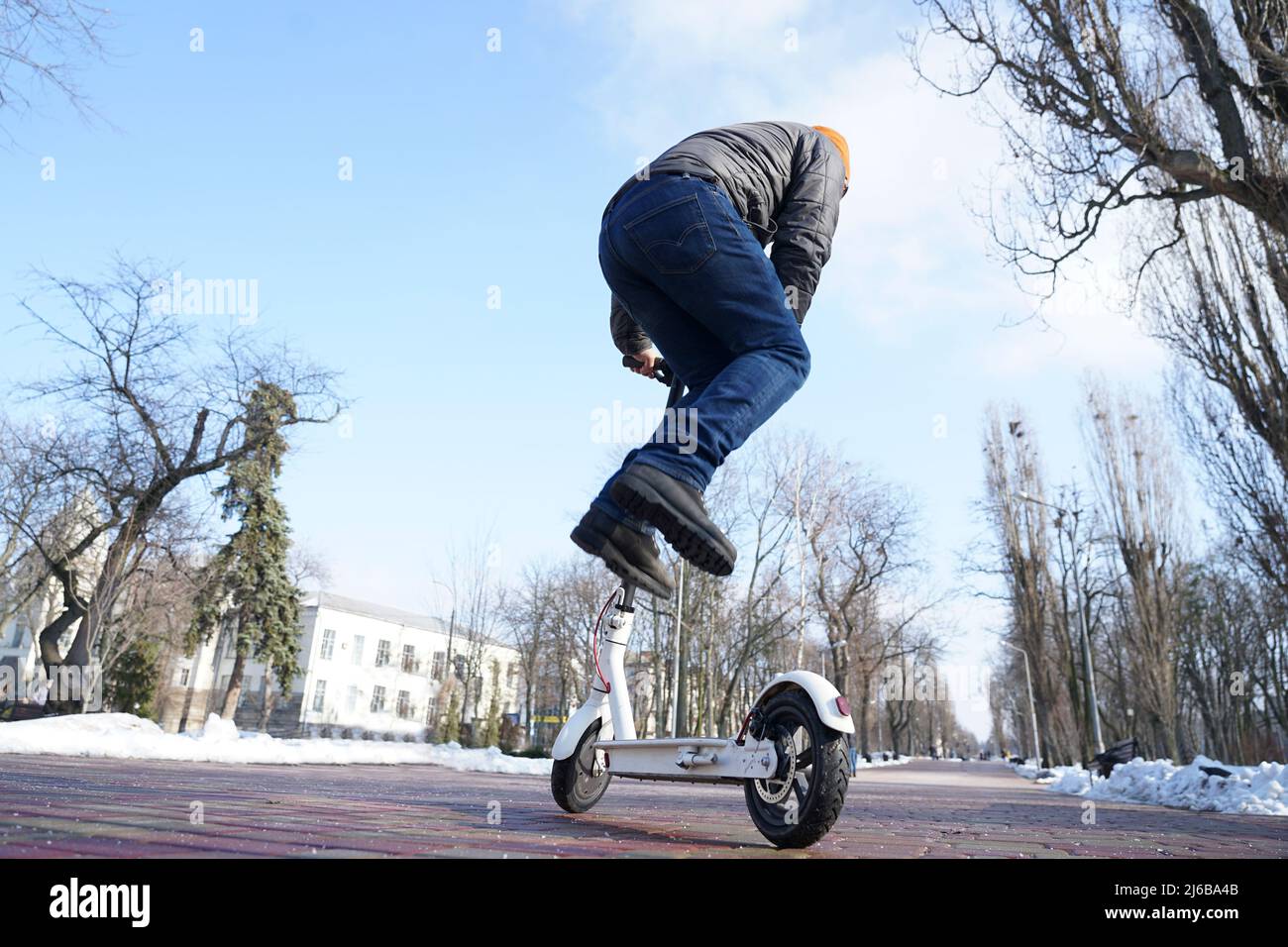 Der Typ fährt und springt im Frühjahr im Park einen Elektroroller Stockfoto