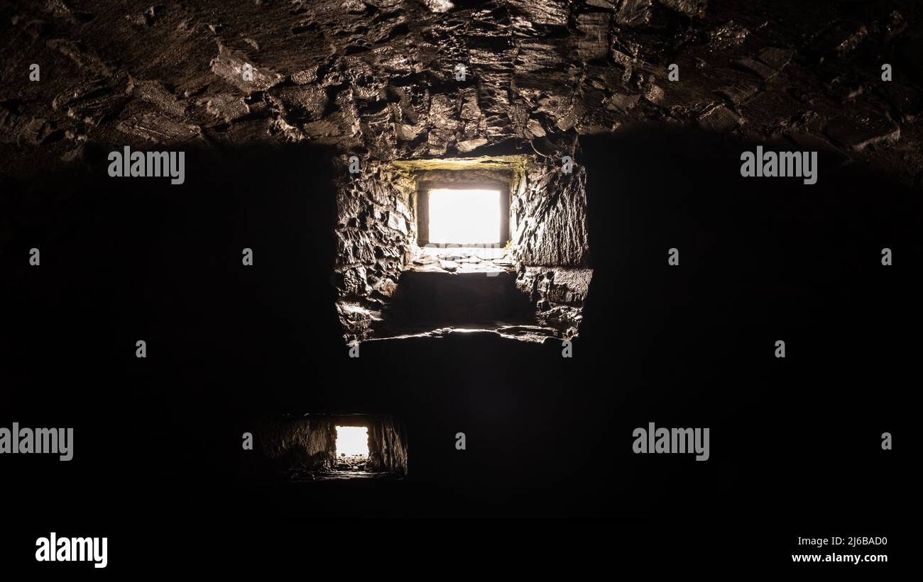 Licht, das durch ein dunkles, steinernes, ein Burggefängnis oder ein Dungeon-Fenster scheint Stockfoto