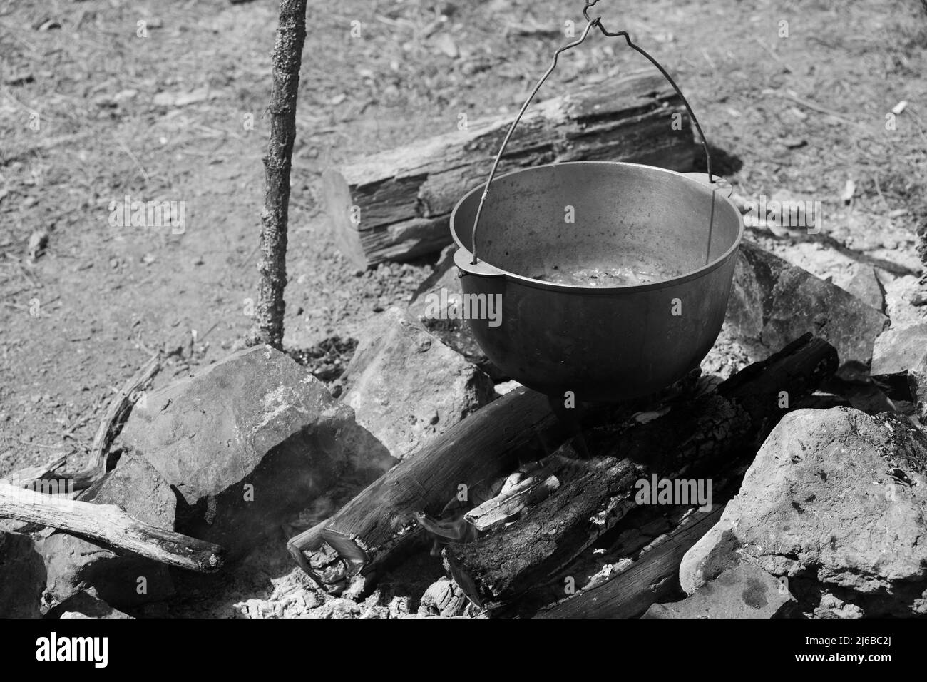 Touristensuppe mit Gemüse kocht in einem Kessel. Vorbereitung auf ein offenes Feuer, Camping-Mahlzeit. Schwarzweiß-Foto Stockfoto