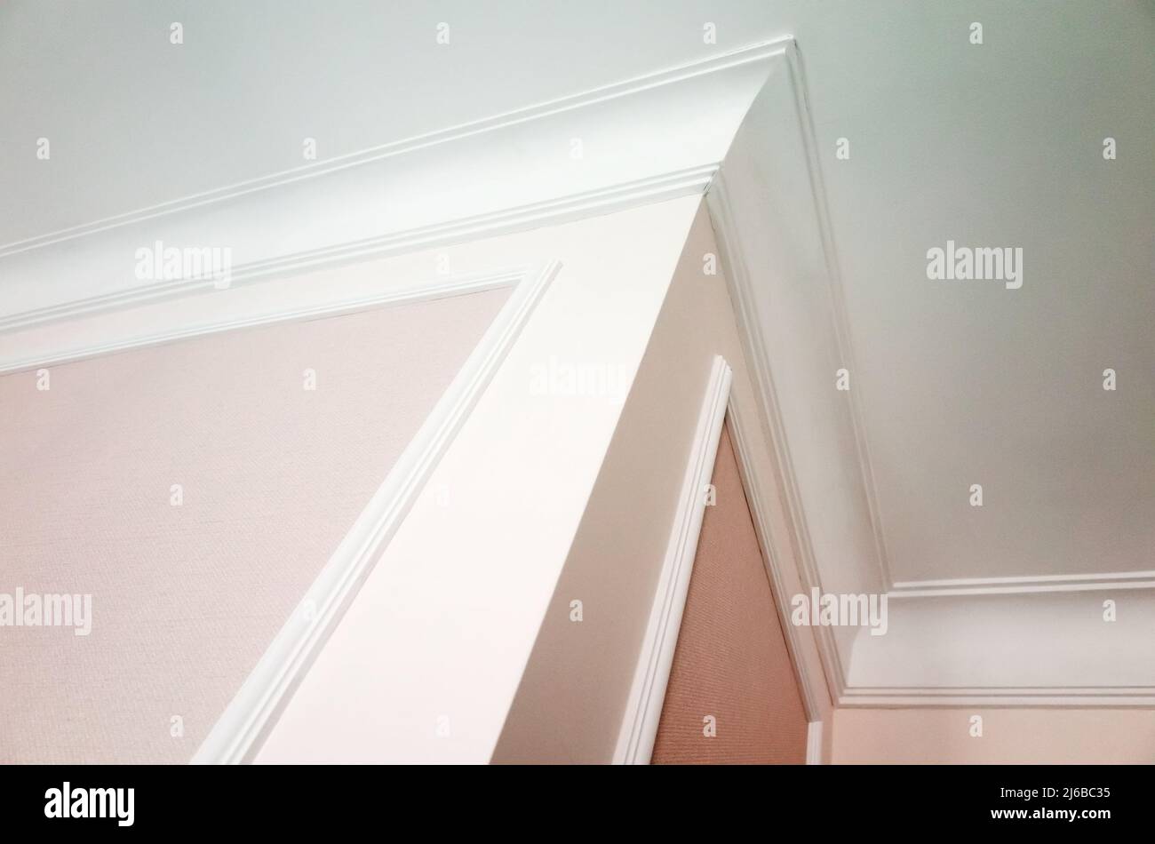 Abstrakte klassische Architektur Hintergrund Foto mit weißen Deckendetails und rosa Wände Dekoration. Fragment der Innenausstattung im Vintage-Stil Stockfoto