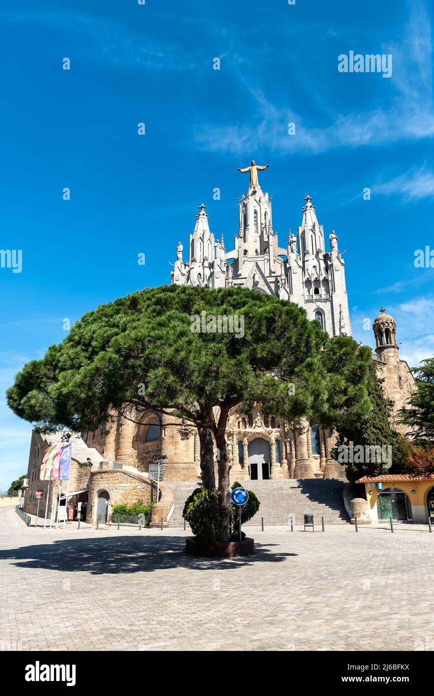 Kathedrale von Tibidabo in Barcelona, Spanien. Tempel des Heiligen Herzens Jesu am Berg Tibidabo. Hoher Baum und blauer Himmel mit Wolke des Sommertages. Stockfoto