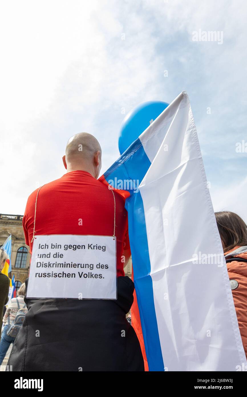 30. April 2022, Sachsen, Dresden: Ein Mann hat auf dem Rücken ein Schild mit der Aufschrift: "Ich bin gegen Krieg und Diskriminierung des russischen Volkes". Rund 100 Menschen sind zur prorussischen Kundgebung auf dem Theaterplatz in Dresden gekommen, die den Titel „Weltfrieden, kein Krieg in Europa, Völkerverständigung, keine politische Propaganda in den Schulen“ trägt. Foto: Daniel Schäfer/dpa Stockfoto