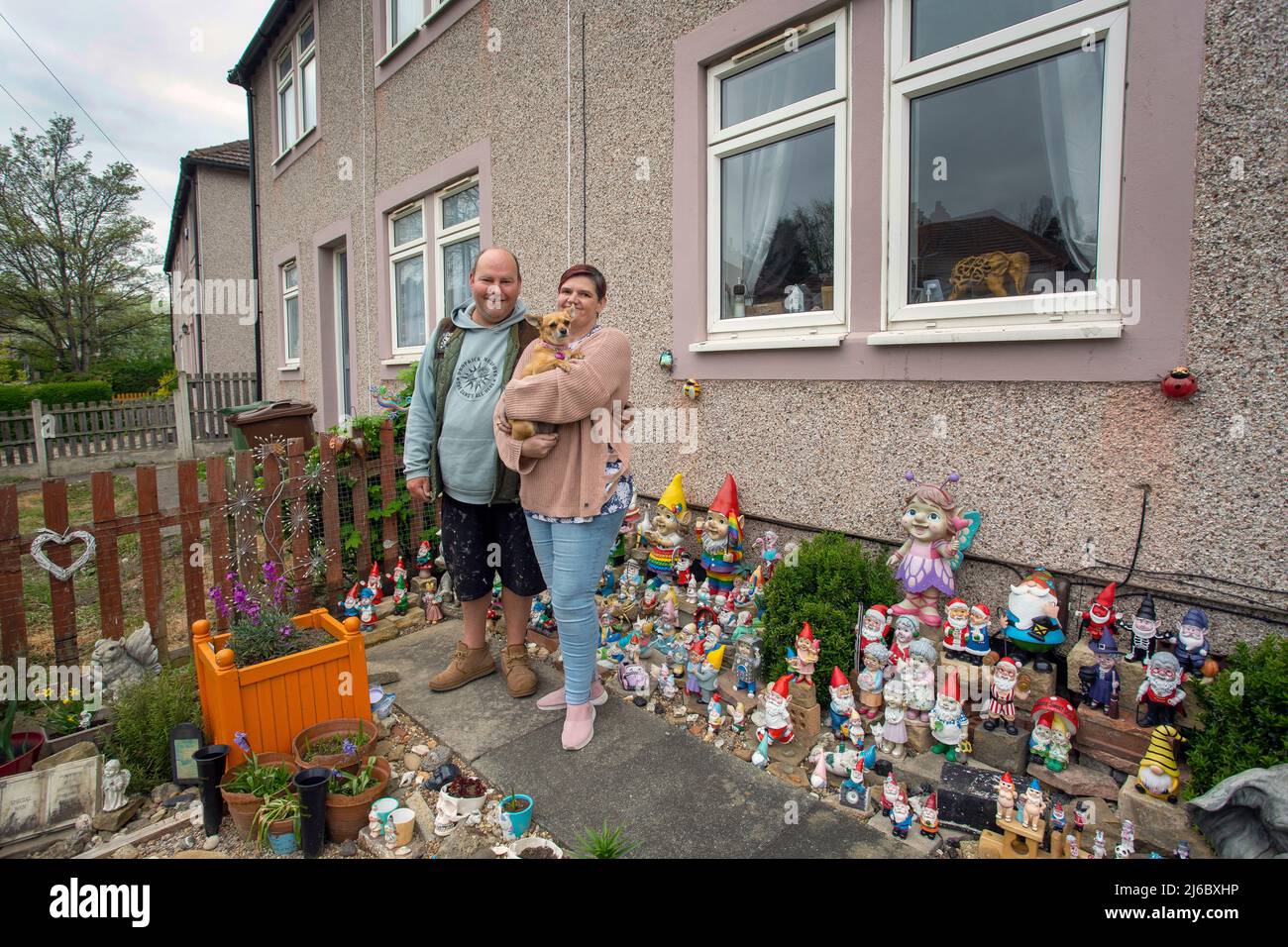 Nicola und Lee posieren vor ihrer Sammlung von Gartengnomen vor einem Reihenhaus in Luset, Wakefield, West Yorkshire, England. Stockfoto