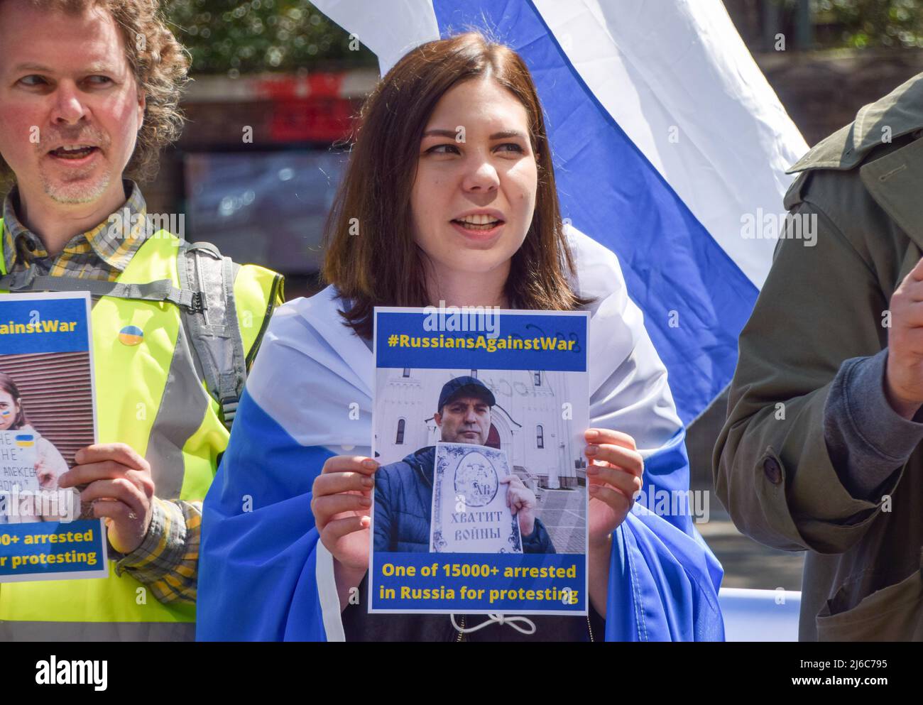 30. April 2022, London, England, Vereinigtes Königreich: Ein Protestler, eingewickelt in eine symbolische blau-weiße Anti-Kriegs-russische Flagge, hält ein Schild mit einem Foto eines Protesters, der in Russland verhaftet wurde. Die ukrainische Solidaritätskampagne und die Russen gegen den Krieg veranstalteten vor der russischen Botschaft in London einen Protest, der ein Ende des Krieges und die Freilassung politischer Gefangener in Russland forderte. (Bild: © Vuk Valcic/ZUMA Press Wire) Stockfoto