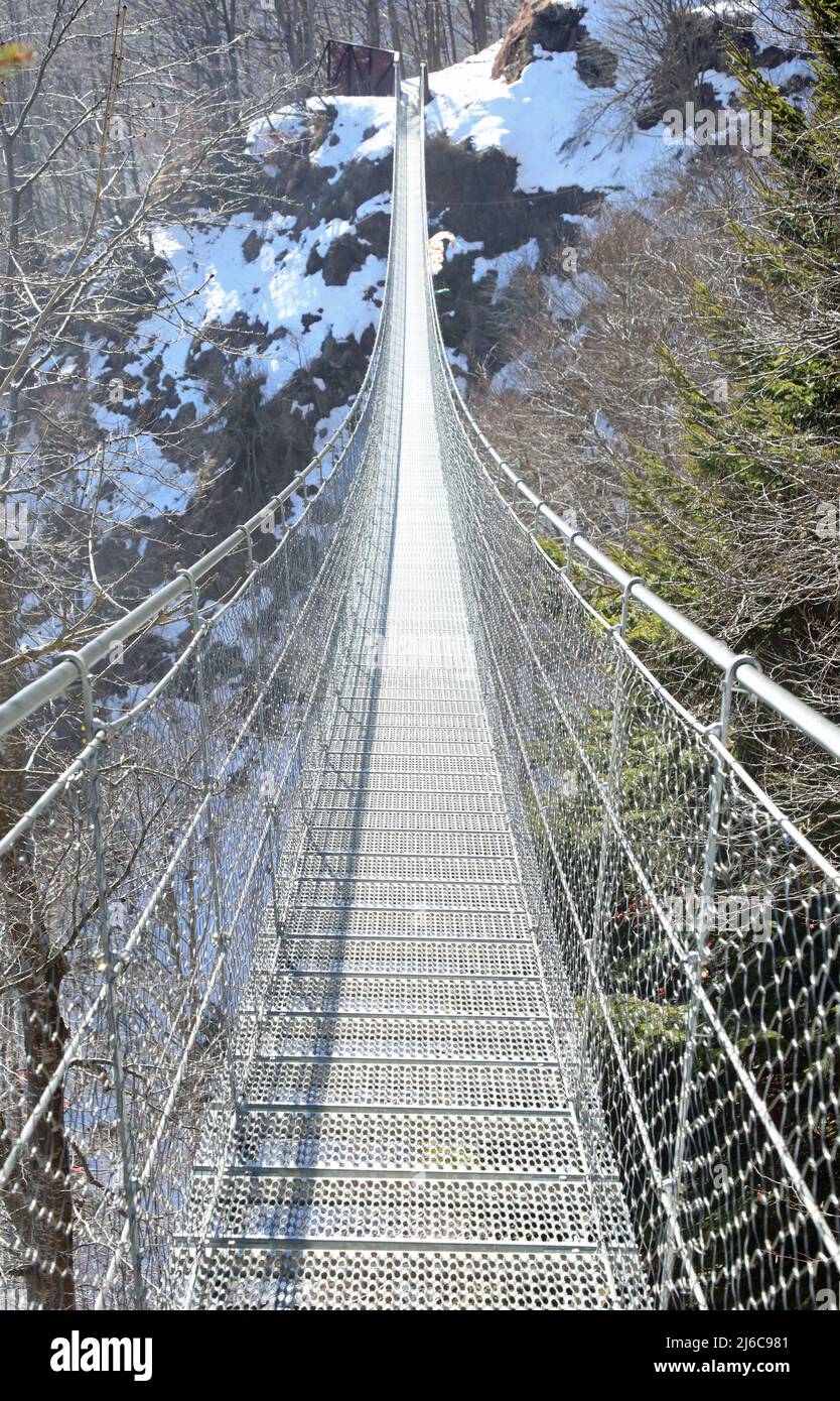 Hängebrücke aus Metall mit Stahlseilen im Winter auch als tibetische Brücke über die Berge bezeichnet Stockfoto