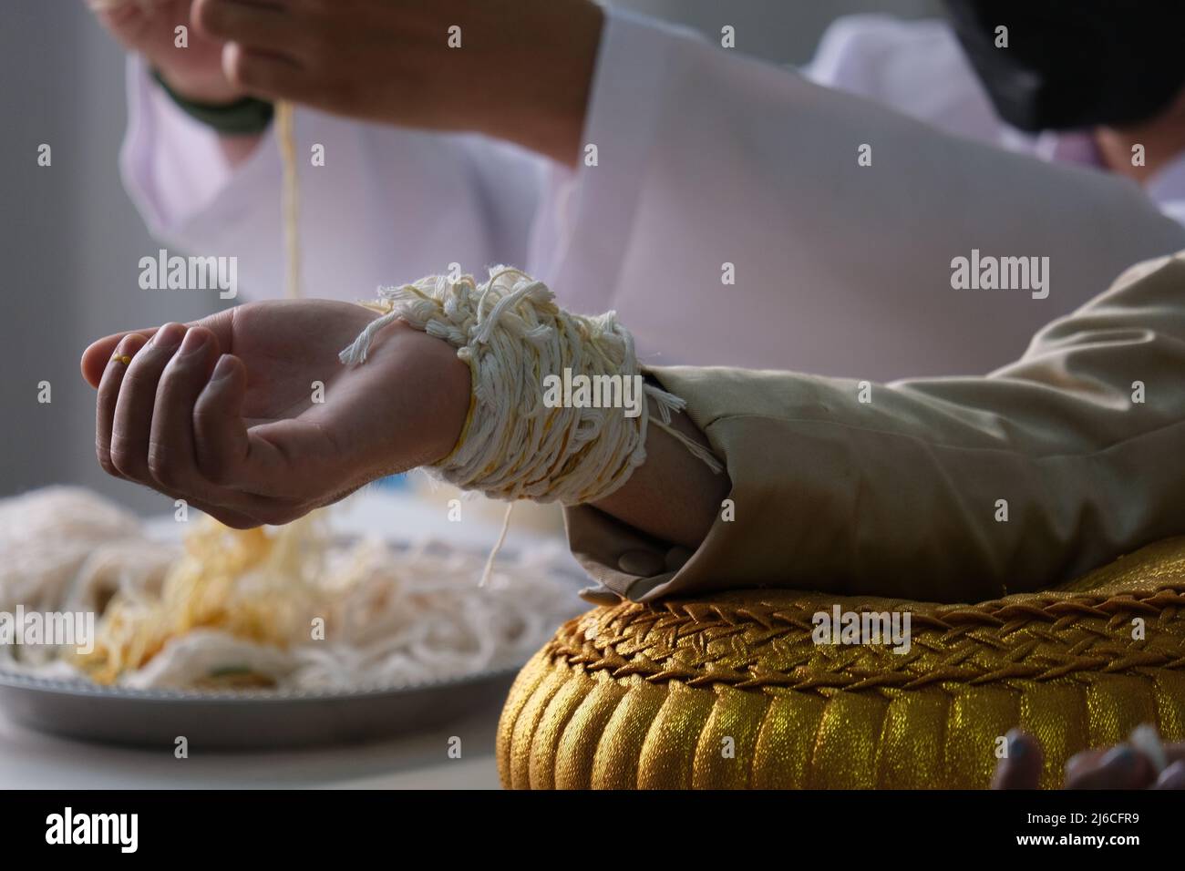 Thailändische Hochzeit: Viele Armbänder am Arm des Bräutigams, die von Gästen als Glückswunsch gebunden werden. Es sollte von Bräutigam und Braut drei Tage lang getragen werden Stockfoto