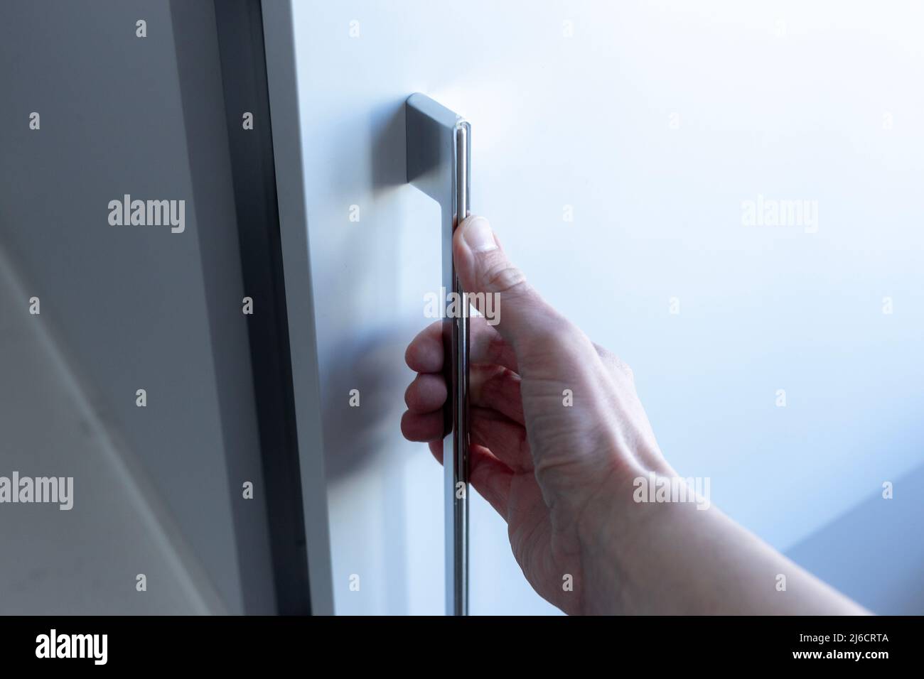 Eine Hand, die eine Schranktür öffnet. Stockfoto