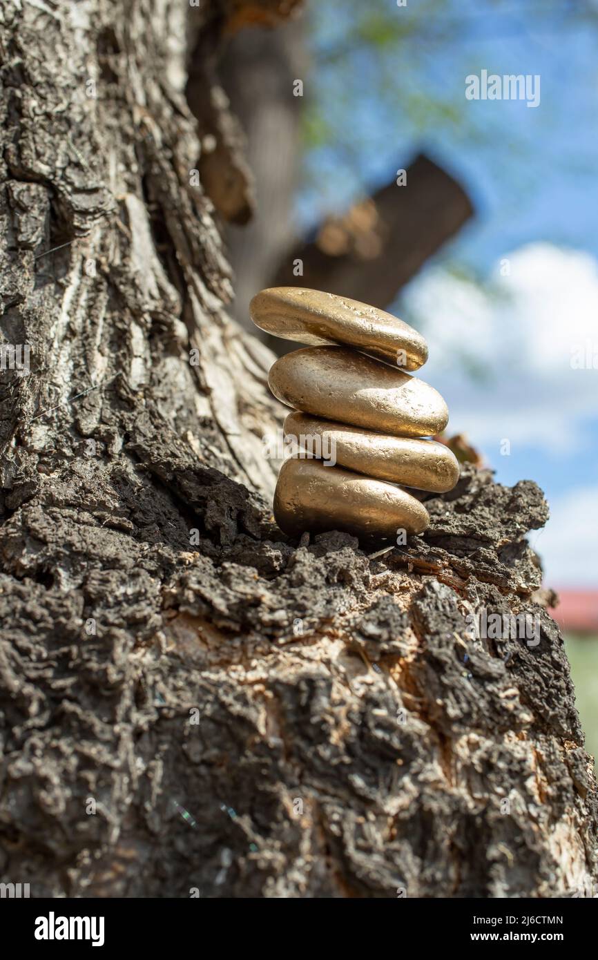 Goldene Steine auf einem Baum gestapelt, abstraktes Zen-Konzept Stockfoto