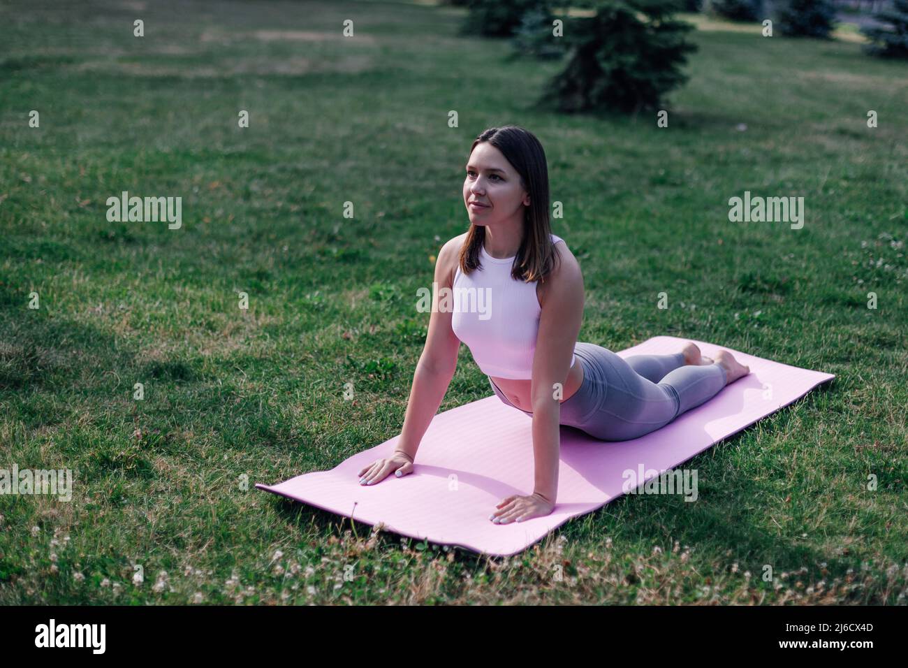 Junge Frau macht Yoga. Attraktive Frau in Sportkleidung liegt auf Übungsmatte in Cobra Pose, Durchführung Bhujangasana Übung Stockfoto