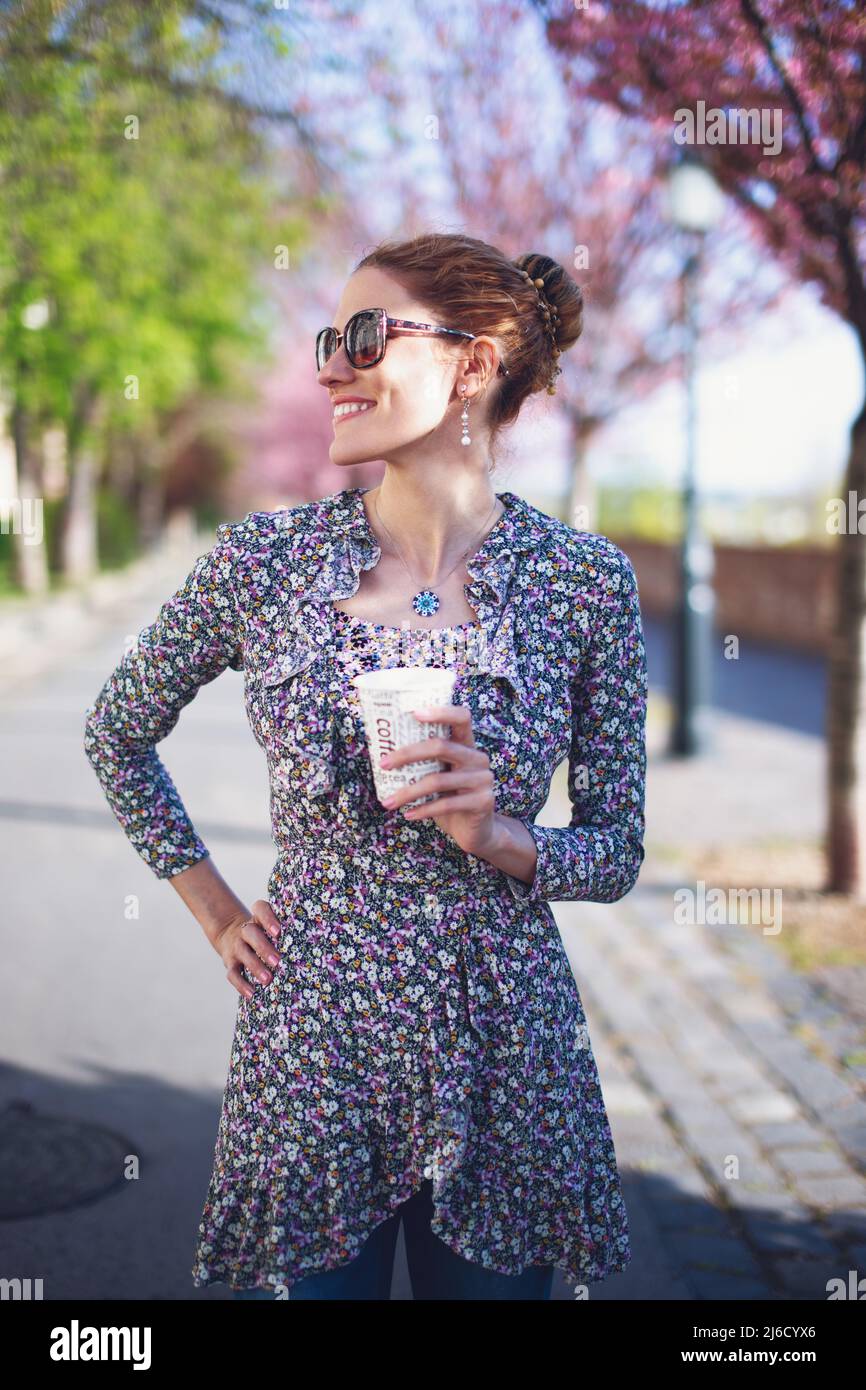 Glückliche junge positive Rotschopf weiße Frau hält Kaffee im Freien Stockfoto