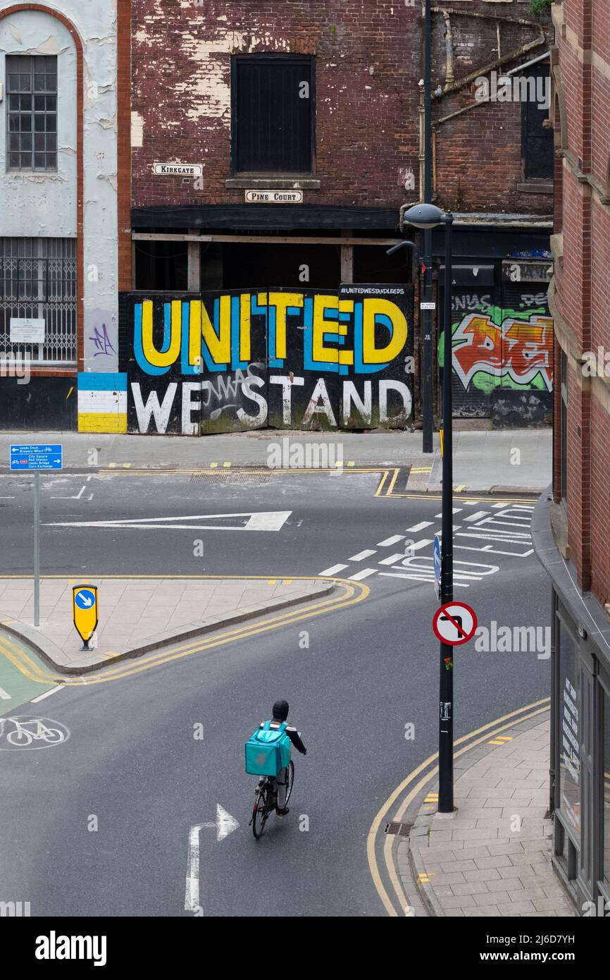 Deliveroo Rider cycling towards United We Stand Wandbild, Pine Court, Leeds Stockfoto