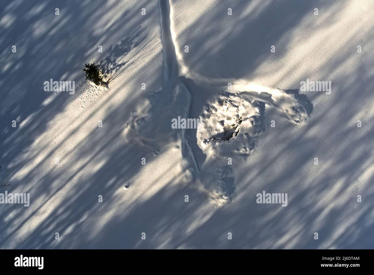Konzeptionelle Luftaufnahme von Spuren im Schnee mit diagonalen Schatten. Stockfoto