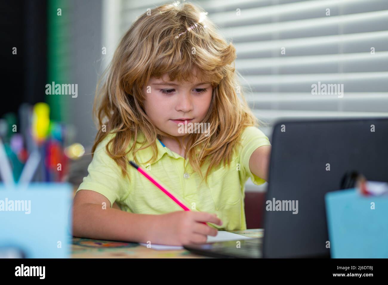 Schuljunge macht Hausaufgaben schreiben und lesen zu Hause. Konzentriertes Schreiben von Kindern im Notizbuch. Fokussierter Schuljunge, der studiert und sich auf Prüfungen vorbereitet. Stockfoto