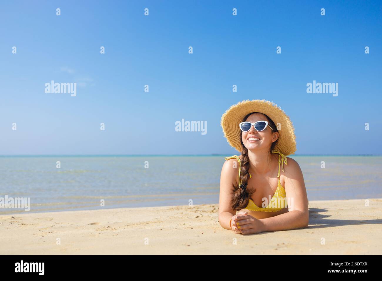 Lächelnde Frau mit Weihnachtshut und Sonnenbrille am Sandstrand Stockfoto