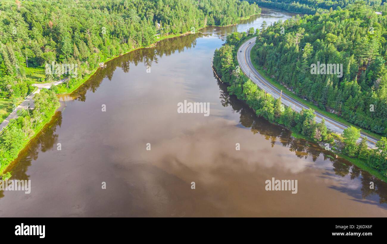 Luftaufnahme des Gatineau Flusses in der Nähe des Dorfes Wakefield, Kanada. Wolken, die sich im Flusswasser spiegeln, schlängelt sich eine Straße mit Autos entlang des Kurses Stockfoto