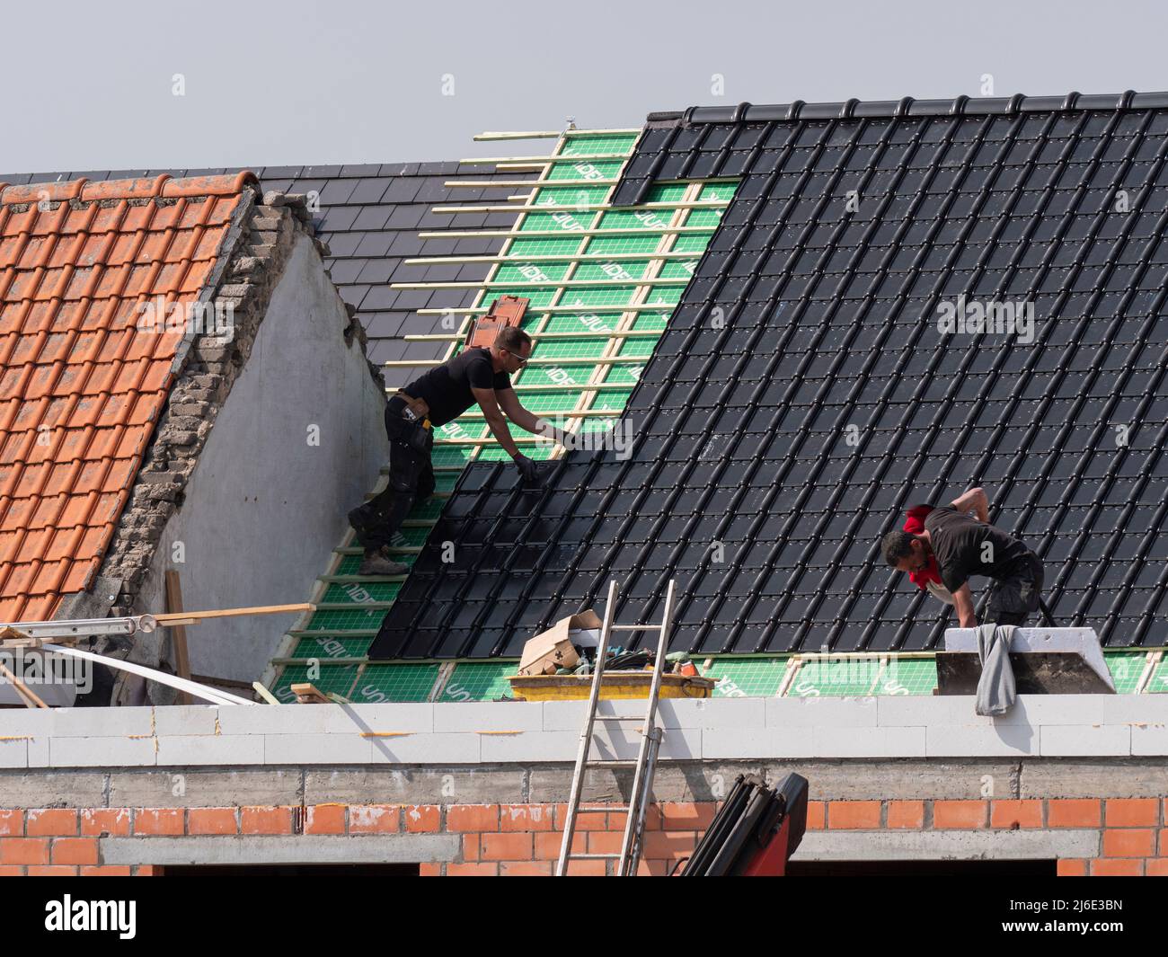Sint Gillis Waas, Belgien, 28. April 2022, Dachdecker setzen dunkle Dachziegel auf ein Haus Stockfoto