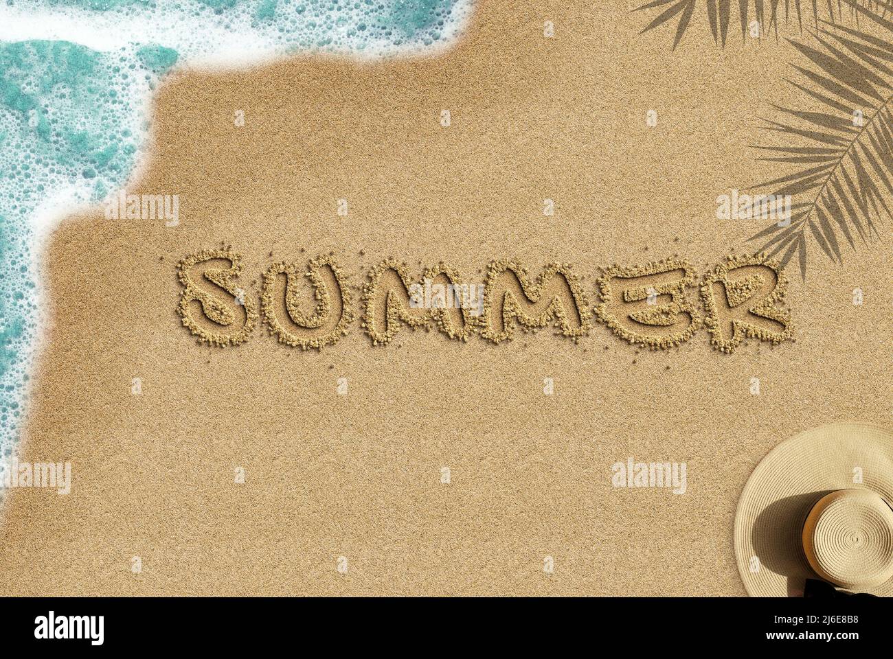 Sommertext am Sandstrand, Draufsicht auf den Sandstrand, Idee der Sommerzeit, Reise- und Urlaubskonzept, Palmschatten und Meereswellen- und Strohhut-Komposition Stockfoto
