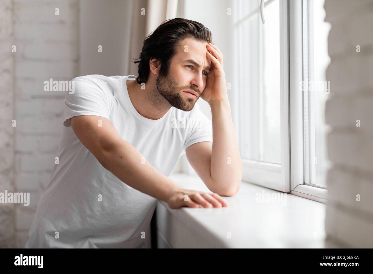 Einsamer junger Mann, der am Fenster steht, Raum kopieren Stockfoto