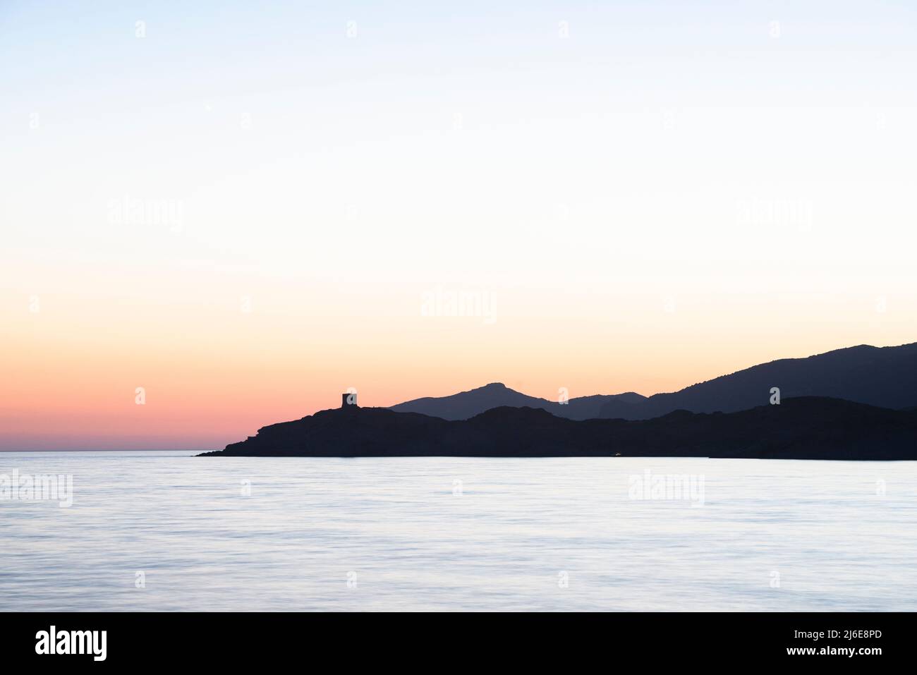 Romantische Landschaft - Abenddämmerung am Meer nach Sonnenuntergang in der Bucht von S'Abba Druche an der Westküste Sardiniens mit Blick auf den Turm am Kap Torre Argentina Stockfoto