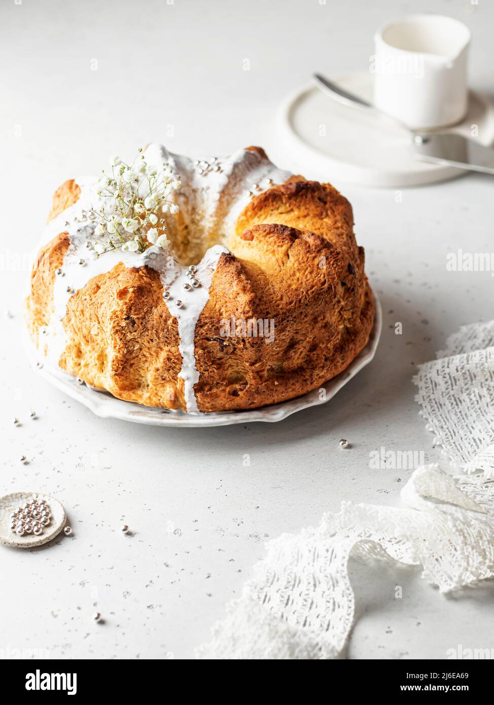Bundt-Kuchen mit Puderstreuseln und Blumen dekoriert. Ostern orthodoxe süße Brot in einem hohen Schlüssel Stockfoto