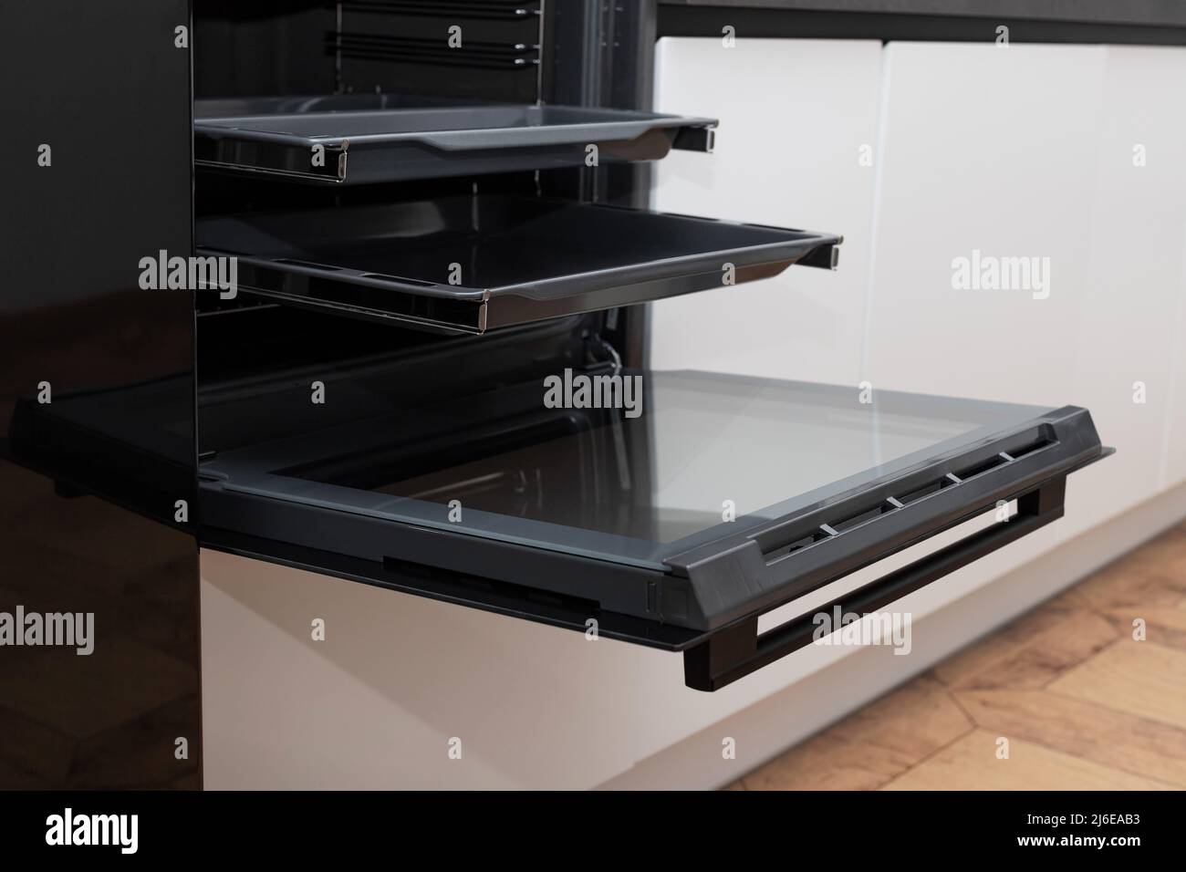 Offener elektrischer Ofen in moderner weißer Küche eingebaut Stockfoto