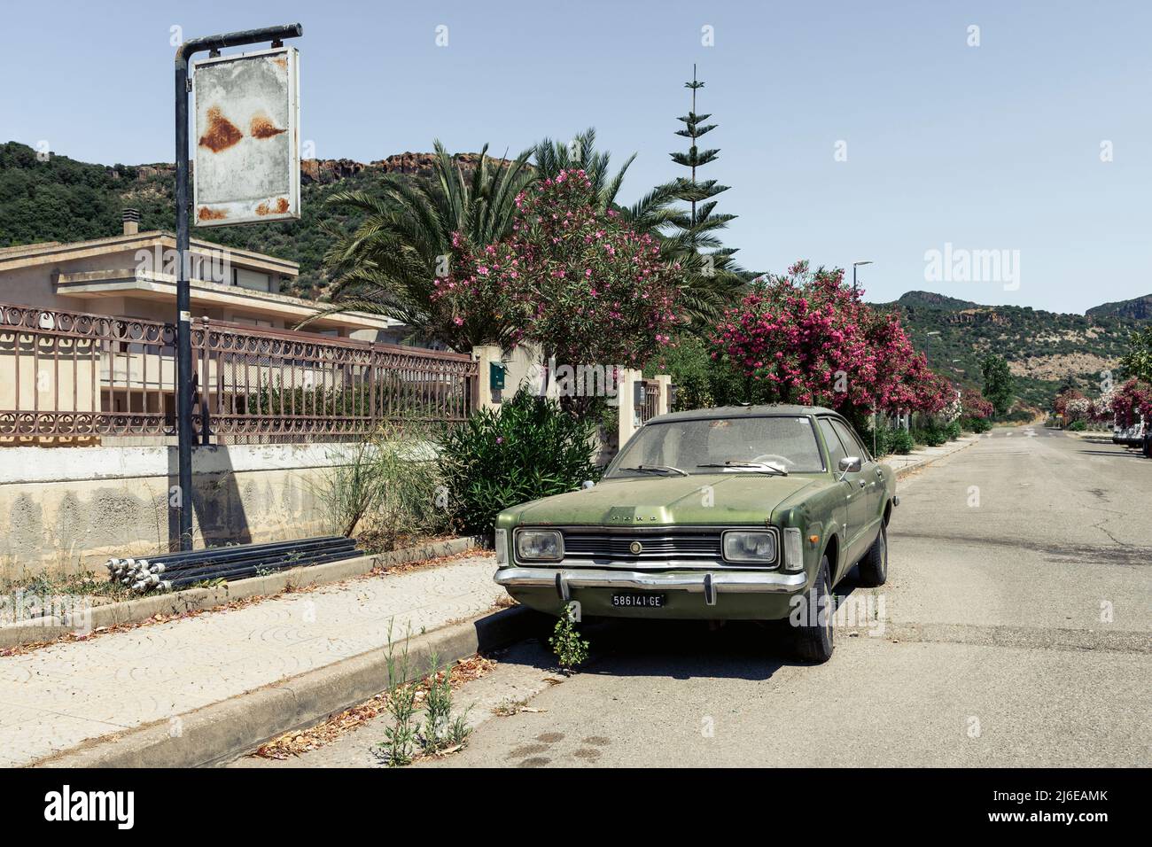Classic Car und Retro Design - alter, staubiger, verwitterter und rostiger Ford Taunus, der in der hellen Mittagssonne Bosa, Sardinien, am Straßenrand geparkt ist Stockfoto
