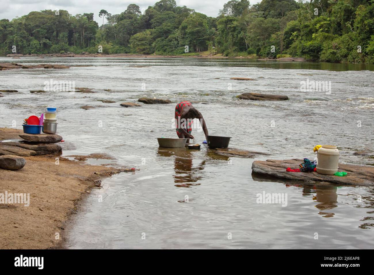 Frau putzt Haushaltsgegenstände im Fluss in Surinam Stockfoto