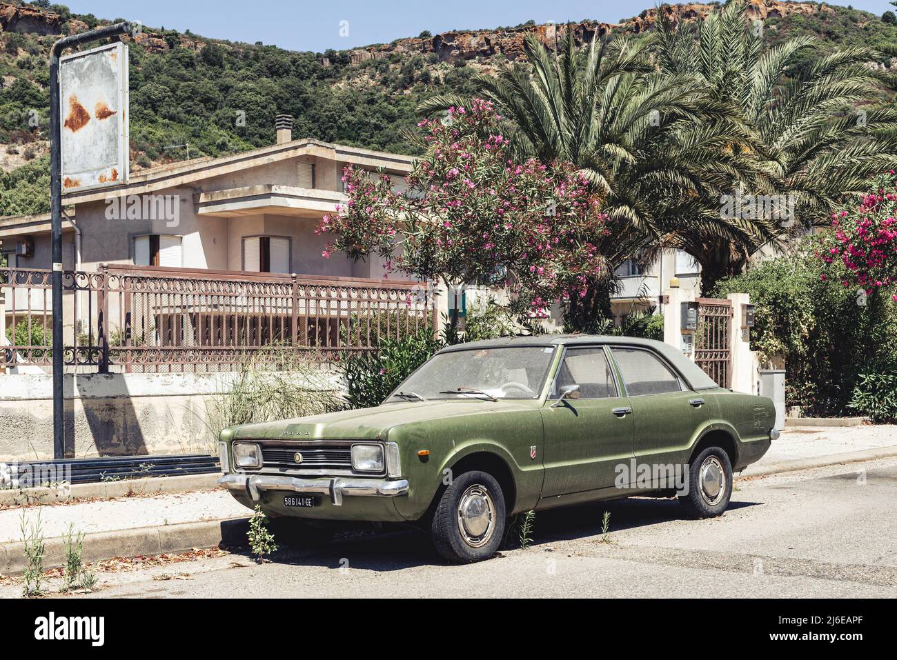 Classic Car und Retro Design - alter, staubiger, verwitterter und rostiger Ford Taunus, der in der hellen Mittagssonne Bosa, Sardinien, am Straßenrand geparkt ist Stockfoto