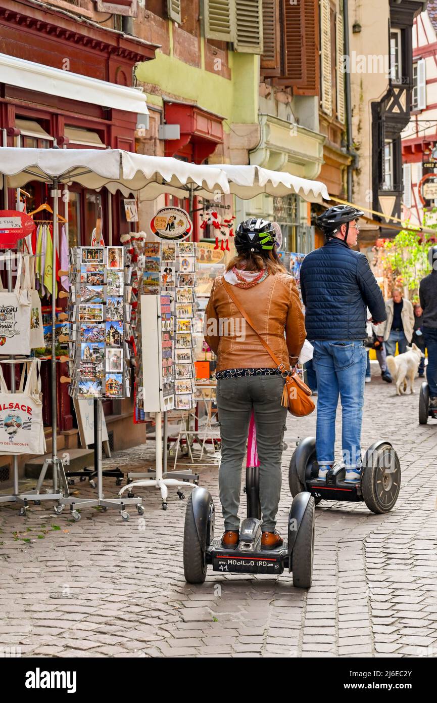 Colmar, Frankreich - April 2022: Zwei Menschen fahren auf Segway-selbstbalancierenden Fahrzeugen durch enge Straßen im Stadtzentrum Stockfoto