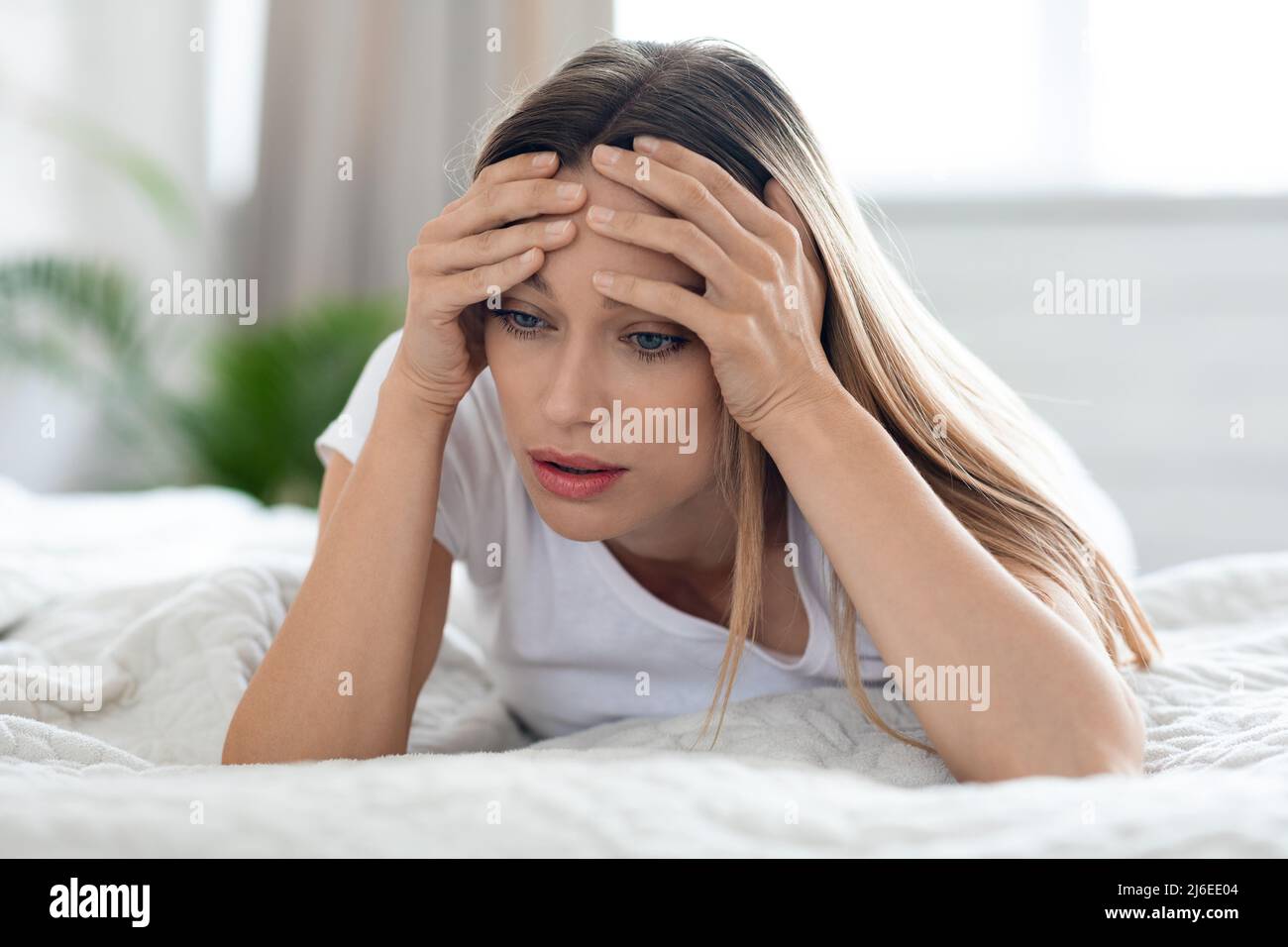 Deprimierte junge Frau, die zu Hause allein im Bett lag Stockfoto