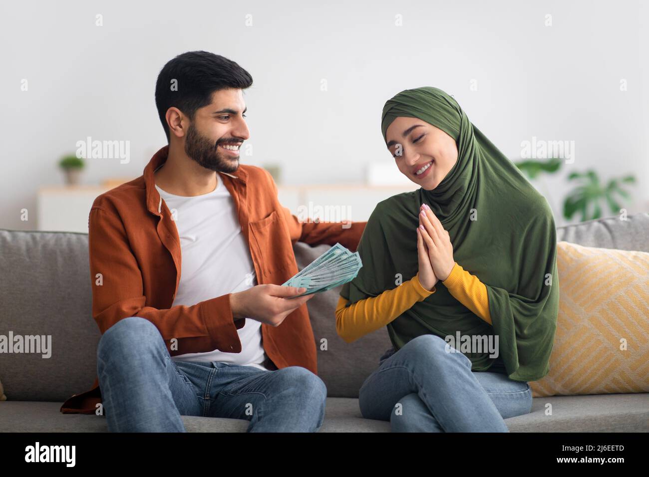 Mann Aus Dem Nahen Osten, Der Der Zu Hause Sitzenden Frau Geld Gibt Stockfoto