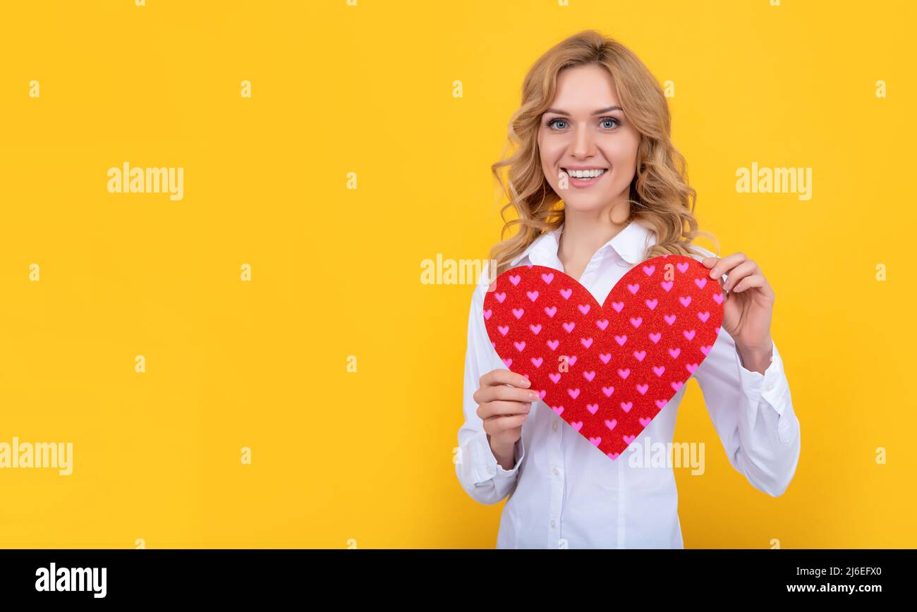 Frohe Frau mit rotem Liebesherz auf gelbem Hintergrund Stockfoto